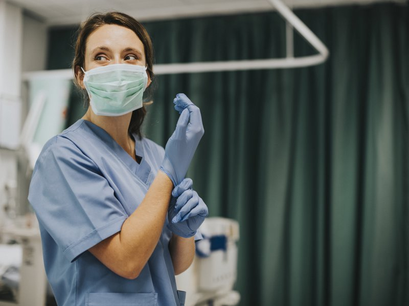 A nurse putting on sterile gloves