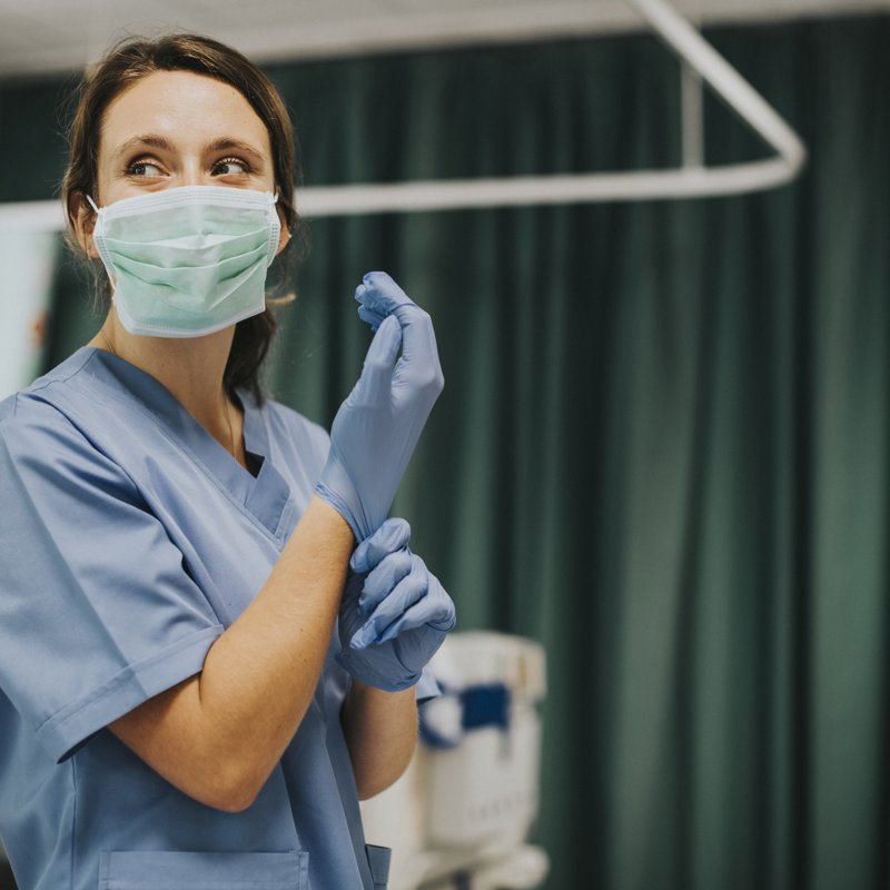 A nurse dons sterile gloves