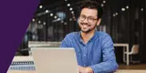 A man smiling while using a laptop