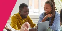 Two people smiling while looking at a laptop