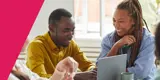 Two people smiling while looking at a laptop