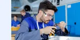A man in safety glasses working on a small widget