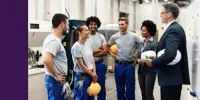 A team with hardhats talking to two people in suits